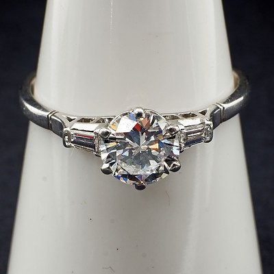Platinum Ring with at Centre a Round Brilliant Cut Diamond 0.90ct (F/G VS2) in a Six Claw Pierced Setting, On either Side a Tapered Baguette Diamond
